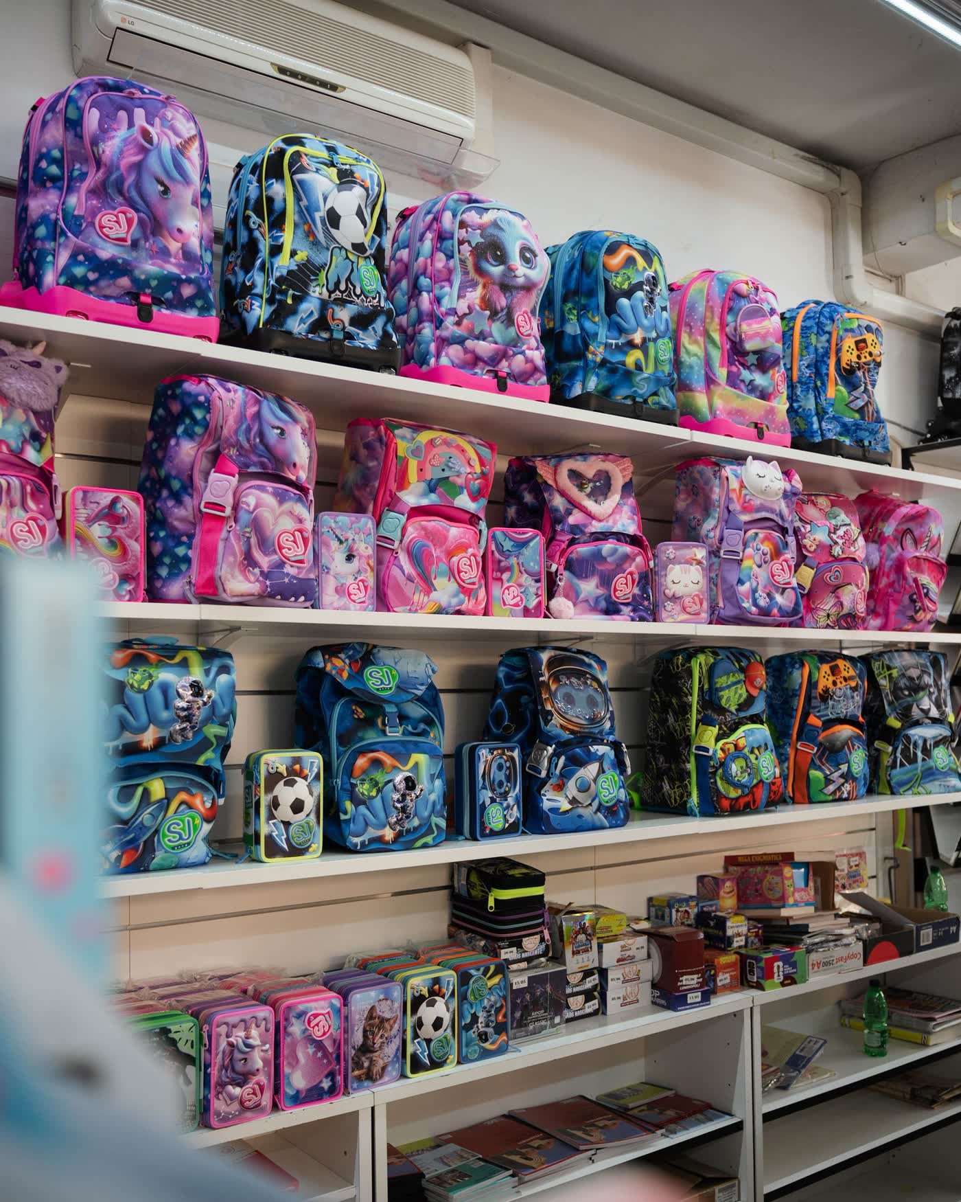 Zaini e materiale scolastico esposti sugli scaffali della Cartoleria Tosi